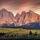 "Seiser Alm, Dolomiten" in weißer Schrift. Kalender über den März. Majestätische Berge im Sonnenuntergang und grüne Wiesen.
