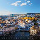 Kalendertext: "Zürich 3". Stadtansicht mit Fluss, alten Gebäuden, Kirchturm mit Uhr, bunte Herbstbäume im Hintergrund.