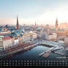 Text: "Jungfernstieg mit Rathaus" und "3". Panorama einer Stadt mit Wasser, Gebäuden und Türmen unter klarem Himmel.