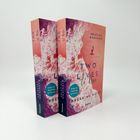 Zwei Bücher mit dem Titel "Two Lives to Rise" von Kristina Moninger. Cover zeigt Wellen und eine Person auf pinkem Hintergrund.