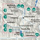Text oben links: "KOMPASS". Zwei Personen studieren eine ausgebreitete Karte auf einem Holztisch im Freien.