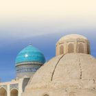 BUCHARA UND UMLAND. Sandfarbene und blaue Kuppeln mit feinem Mosaik vor einem klaren, blauen Himmel.