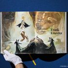 Text: "Frank Frazetta". Ein dekoratives Gemälde mit einer Frau, Felsen und einem großen Vogel im Hintergrund.