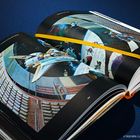 Buch mit dem Text "IMAGINED WORLDS - SCIENCE FICTION AND FANTASY", zeigt ein Raumschiff in einer futuristischen Szene.