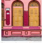 Kalender: 09-15 August 2027. Zwei gelbe Türen mit verzierten Bögen auf rosa- und purpurfarbenem Gebäude.