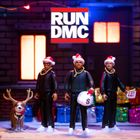 RUN DMC-Logo über drei Figuren in Weihnachtsmannmützen mit Geschenken. Ein Rentier ist ebenfalls dabei.