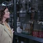 Eine Frau betrachtet Kristallglas in einem Schaufenster. Ihre Reflexion ist sichtbar.