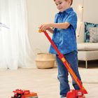 Ein Kind spielt mit einem Spielzeug-Kran und Feuerwehrauto in einem gemütlichen Raum mit Lichterkette.