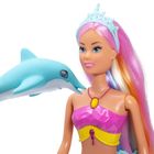 Puppe mit mehrfarbigem Haar, Krone und buntem Oberteil, neben einem blauen Spielzeug-Delfin.