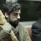 Ein Mann mit lockigem Haar hält eine orange Katze, neben ihm sitzt ein älterer Mann mit Hut in einer Bahn.