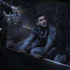 Ein Mann in einem durch Kabel und Technik vollgestopften, dunklen Raum schaut nach oben, sieht besorgt aus.