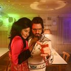 Ein Mann im Elvis-Kostüm und eine Frau posieren in einem Raum mit Disco-Beleuchtung und Holzmöbeln.