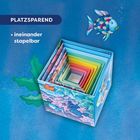 "PLATZSPAREND, ineinander stapelbar." Bunte ineinander gestapelte Boxen mit einem glitzernden Fisch und Pflanzen umgeben.