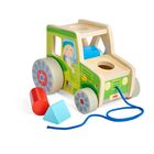 „HABA“ auf einem grünen Holzspielzeug-Traktor mit bunten Bausteinen und blauer Schnur.