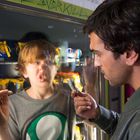 Das Wort "OVERKILL" ist grün geschrieben. Ein Junge mit verzerrtem Gesicht steht an einem Snackautomaten. Ein Mann hält Geld.