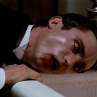 Ein Mann in einem Anzug liegt mit blutendem Gesicht über einer Badewanne.