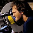 Ein Mann schaut durch den Sucher einer großen Filmkamera, fokussiert und konzentriert.