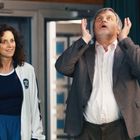 "TC" auf einer weißen Jacke. Vier Personen, lächelnd, einer schaut nach oben, verschieden gekleidet, in einem Raum.