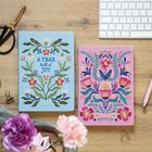 Links steht "A YEAR full of JOY 2027" auf einem blauen, floralen Notizbuch, rechts ein rosa florales Notizbuch.