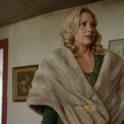 Ein Raum mit antiker Einrichtung. Eine Person trägt einen beigen Umhang. Hintergrund: ein geöffnetes Fenster.