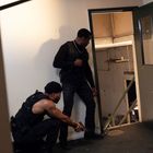 Zwei Männer in taktischer Ausrüstung an einer offenen Tür, einer hockend mit Waffe, der andere schaut in den Raum.