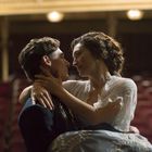 Zwei Menschen tanzen innig in einem gedämmten Theatersaal, umgeben von leeren, roten Sitzen.