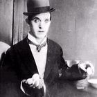 Ein Mann mit Melone jongliert mit Eiern, trägt einen Anzug und schaut ernst.