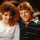 Zwei lächelnde Menschen, Arm in Arm auf einem dekorativen Sofa; sie trägt ein Spitzenoberteil, er ein gestreiftes Hemd.