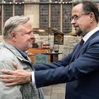 „Brötmobil“ steht auf einem Schild. Zwei Männer stehen sich draußen gegenüber und schauen sich ernst an.