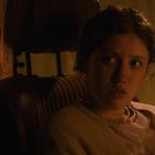 Eine Person sitzt im Auto, schaut zur Seite, mit warmem Licht beleuchtet.