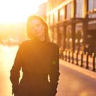 Eine Frau steht auf einer sonnenbeschienenen Straße. Die Sonne sorgt für helle, goldene Lichteffekte.