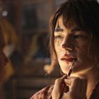 Eine Person wird als Clown geschminkt, mit roten Lippen und schwarzem Dreieck über den Augen.