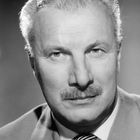 Ich weiß nicht, wer diese Person ist. Ein älterer Mann mit hellem Haar und Schnurrbart trägt einen Anzug und Krawatte.