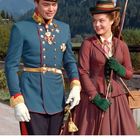 APRIL Kalender, unter einem Mann in Uniform und eine Frau mit Hut, die lächeln. Berge im Hintergrund.