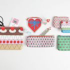 Bunte Taschen mit Mustern wie Herzen und Schleifen, daneben Scheren, Bleistifte, Herzradierer und ein herzförmiges Etui.