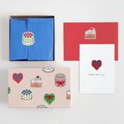 „HAVE A GREAT DAY“ auf einer Karte. „HAPPY BIRTH DAY“ auf einem Aufkleber. Geschenkbox mit Herz- und Kuchenmotiven.