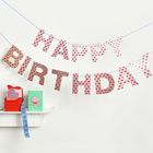 "Happy Birthday" in bunten Buchstaben hängt. Ein Geschenk und eine Karte mit einer Torte darauf stehen auf einem Regal.