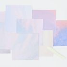 Pastellfarbene quadratische Blätter, dekorative Klebebänder und faltbare Boxen auf hellem Hintergrund.