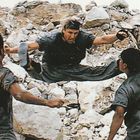 Ich kann den Text nicht lesen. Drei Personen kämpfen, eine in der Luft tretend, umgeben von Felsen.