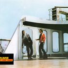 "Toby & Butch: Vier Fäuste geben Zunder." Zwei Männer auf einem Schiff. Einer spritzt Wasser aus dem Mund.