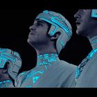 Vier Personen tragen futuristische Helme und Anzüge mit leuchtend blauen Linien.