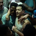 Mehrere junge Erwachsene tanzen und umarmen sich in einer ausgelassenen Partystimmung eng beieinander.