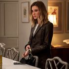 Eine Frau mit blonden Haaren steht an einem Küchentresen, umgeben von eleganten Möbeln und Bildern an der Wand.