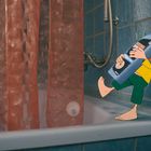 Ein animierter Junge mit rotem Haar trägt eine blaue Shampooflasche, steht in einer Badewanne mit rosa Duschvorhang.