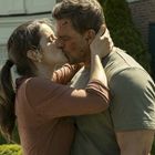 Kein sichtbarer Text. Ein Mann und eine Frau küssen sich innig im Freien, umgeben von einem Garten vor einem Gebäude.