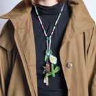 Perlenkette mit Karabiner hält Schlüssel, Häkelblume und Filzanhänger. Getragen über schwarzem Oberteil, brauner Mantel.