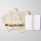 Anleitung Instructions. Beige Stoffe, ein geflochtener bunter Fadenstrang und ein weißes Blatt mit Anleitungsdiagramm.