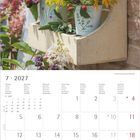 Kalender für Juli 2027. Bunte Blumen in Töpfen auf einem Holzregal an einer Backsteinwand.