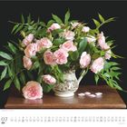 „Margaret Merril“ - Clay Perry. Juli-Kalenderblatt. Vase mit rosa Rosen, grünen Blättern, auf einem Holztisch.