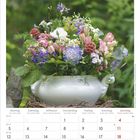 Juli, Juillet, Luglio, July 2027. Kalenderblatt mit Blumenarrangement in einem weißen Gefäß, umgeben von Grün.